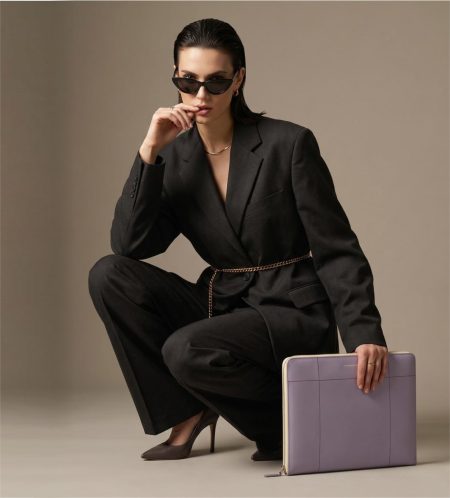An avant-garde fashion photograph of a modern woman crouching on the floor, holding a luxury lavender embossed leather portfolio by STEFAN SERVAL.